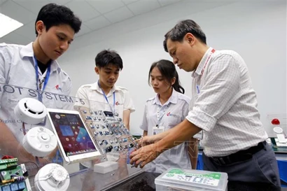 Un enseignant de la Faculté de Technologie électronique de l'Université Industrielle de Ho Chi Minh-Ville guide ses étudiants dans leurs travaux et recherches au laboratoire IoT et Intelligence Artificielle. Photo: VNA