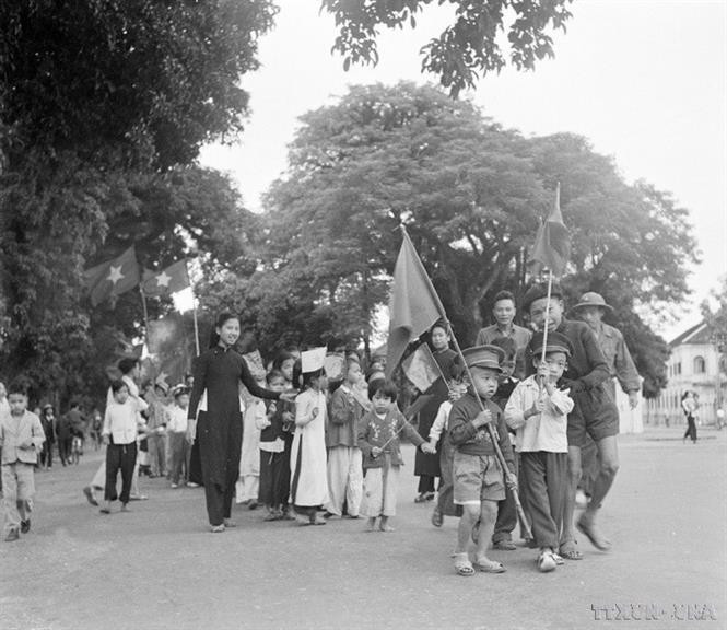 Des enfants de Hanoï, accompagnés de leurs proches, agitent des drapeaux, célébrant l'arrivée des soldats libérateurs. Photo : Archives anh-6.jpg