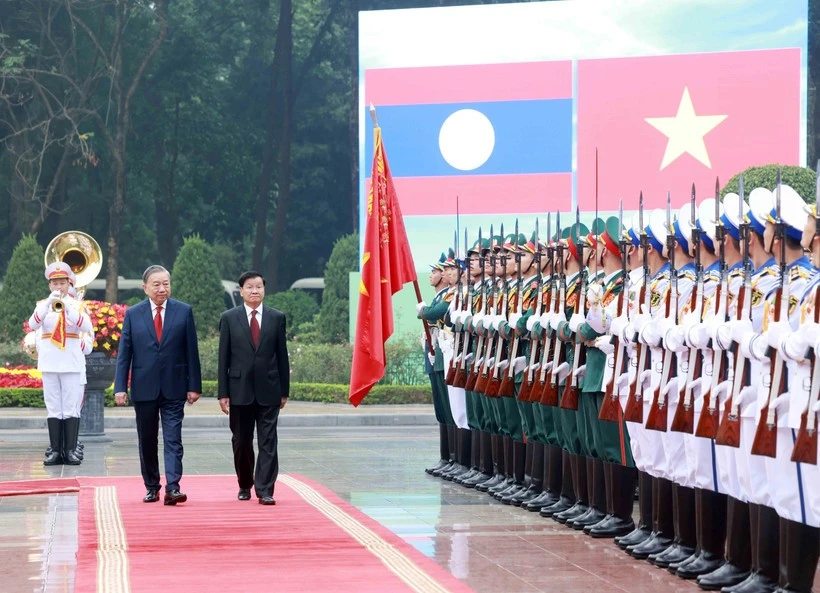 Les dirigeants To Lam et Thongloun Sisoulith passent en revue la garde d'honneur de l'Armée populaire vietnamienne. Photo: VNA