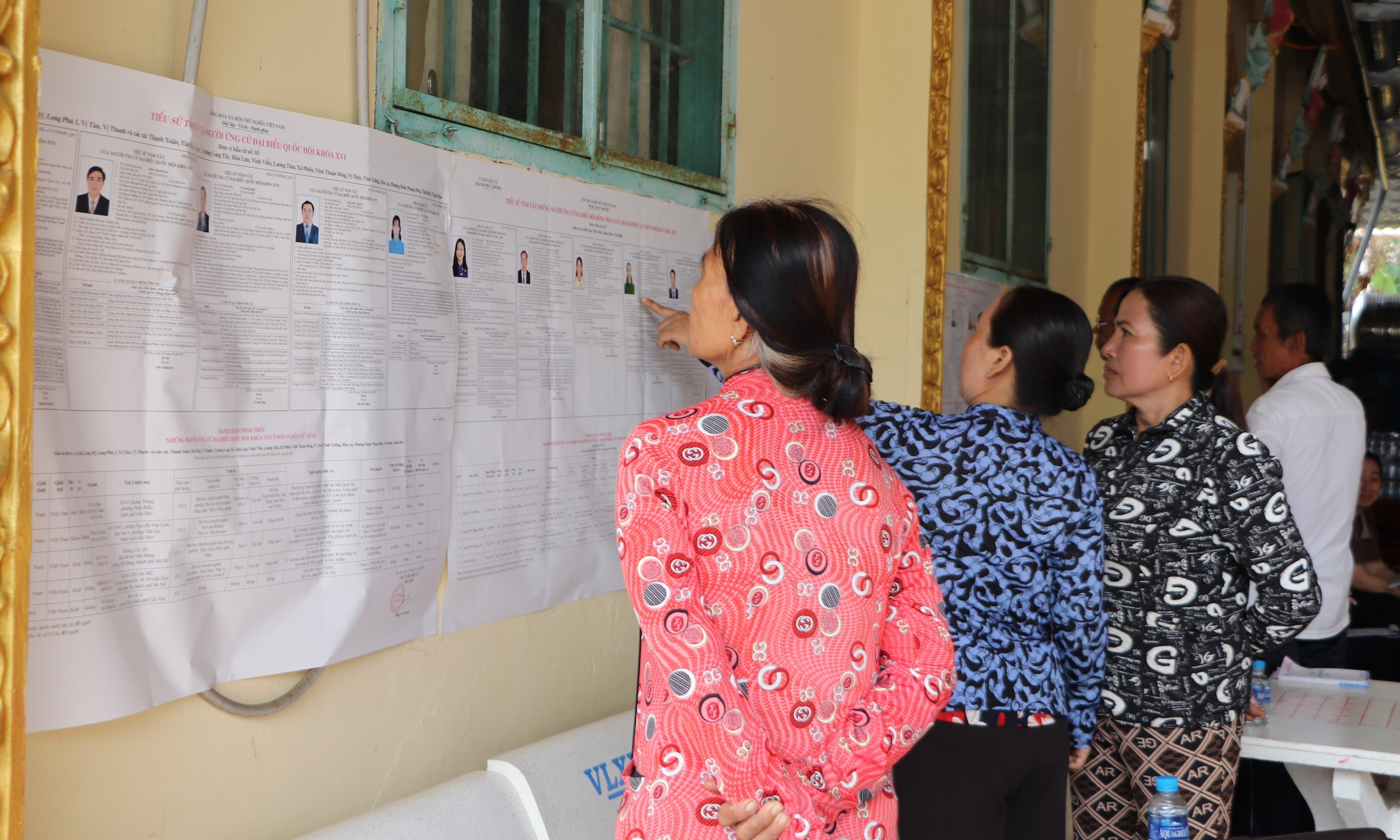 Des habitants khmers du hameau de Ngã Cạy, commune de Xà Phiên, consultent les informations sur les candidats aux élections de l’Assemblée nationale et des Conseils populaires affichées à la pagode Bôrâysarâychum. Photo : VNA.