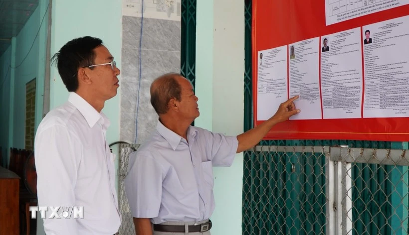 Des électeurs consultent les brèves biographies des candidats au Conseil populaire de la commune de Tan Hong, province de Dong Thap, mandat 2026-2031. Photo : VNA